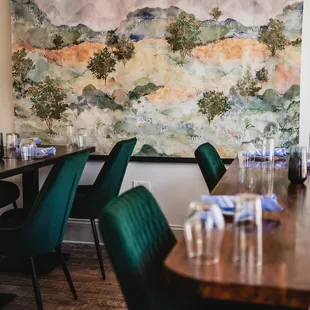 a dining room with a large painting on the wall