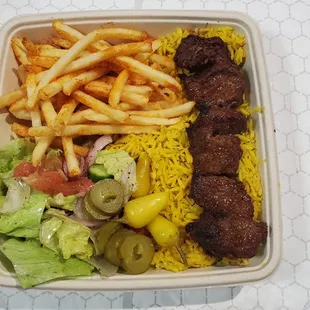 Beef steak kabob plate with rice, salad and fries.