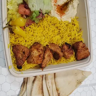 Chicken kabob plate with rice, hummus and salad.
