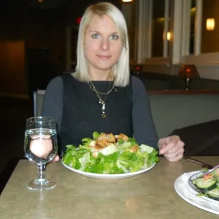 a woman sitting at a table with a plate of salad