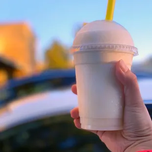 a hand holding a plastic cup with a straw