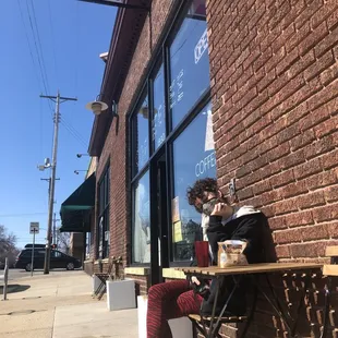 a woman sitting on a bench in front of a brick building