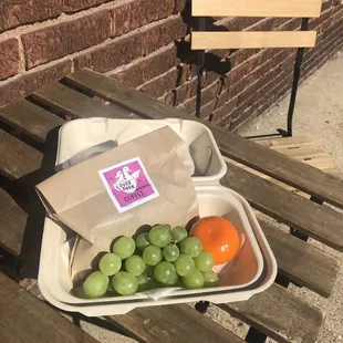 a container of green grapes and oranges