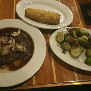 a plate of steak with mushrooms and brussels sprouts