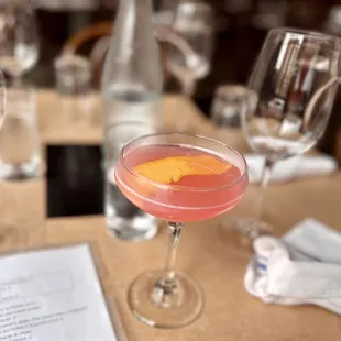 a pink cocktail in a coupe glass on a table
