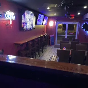 a bar with a row of chairs and televisions on the wall