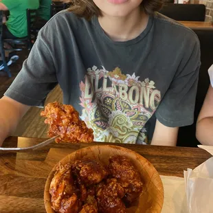 a young boy sitting at a table with a plate of wings