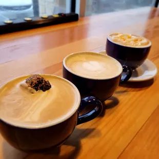 three cups of coffee on a wooden table