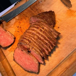 a sliced steak on a cutting board with a knife