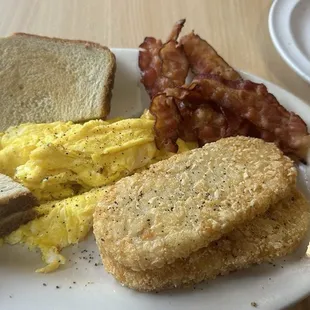 Scrambled eggs, bacon, hash brown patties, sausage patties and toast