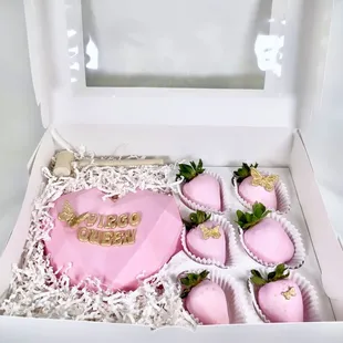 a pink heart shaped cake and cupcakes