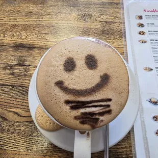 A capuchino coffee with a design of a happy face