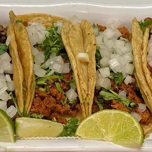 a tray of tacos with lime wedges