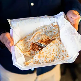 a person holding a bag of quesadillas