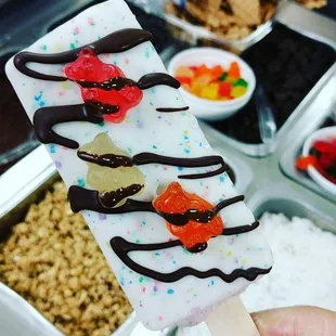 Cheese and blackberry paleta covered with birthday cake white chocolate, gummy bears then drizzled with chocolate