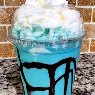 a blue drink with whipped cream and a cherry on top