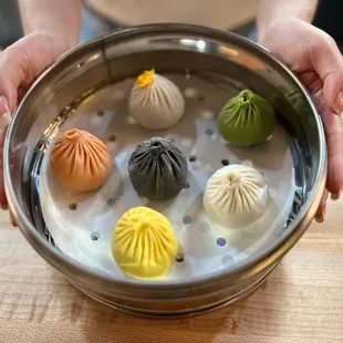 a person holding a bowl of dumplings