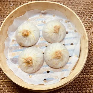 four steamed dumplings in a bamboo basket