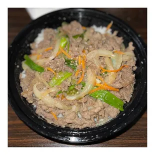 a black bowl of food on a wooden table