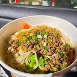 a bowl of noodles with meat and vegetables