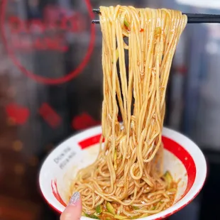  hand holding a bowl of noodles