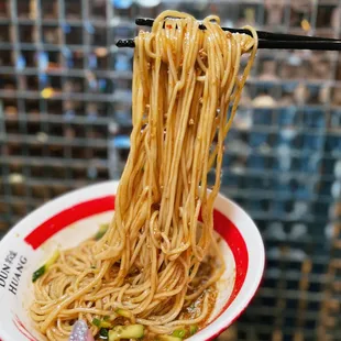  person holding a plate of noodles with chopsticks