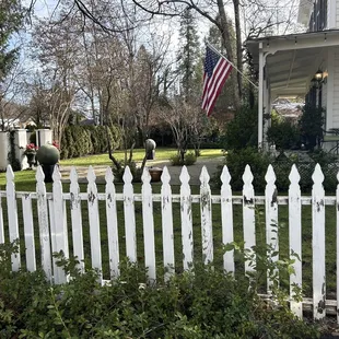 Dilapidated, white picket fence that needs painting and repairs