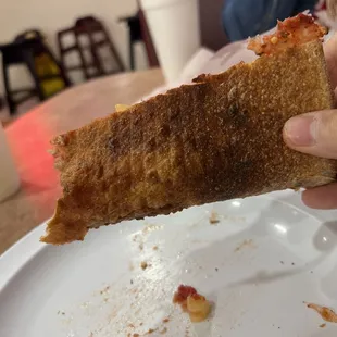 a hand holding a piece of pizza