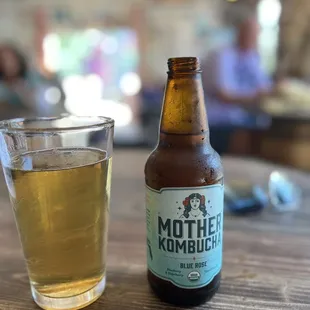 a bottle of mother kombuch next to a glass of beer