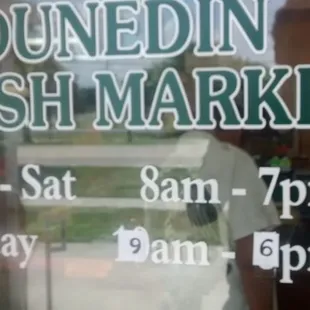a storefront window with a sign that says dunedin fresh market