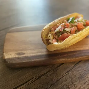 a hot dog on a wooden cutting board