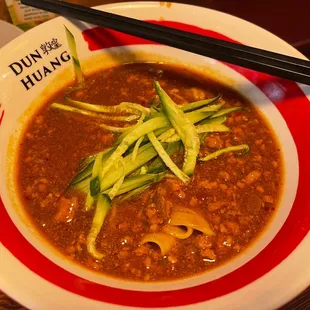 a bowl of soup with chopsticks
