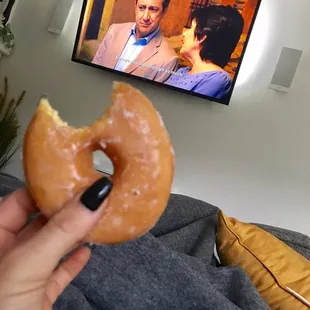  a person holding a donut in front of a television