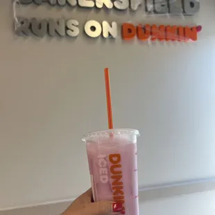  a hand holding a pink drink