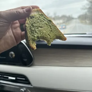a hand holding a piece of bread in a car