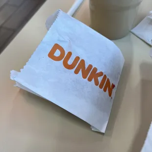  a cup of coffee and a napkin with the word dunkin on it