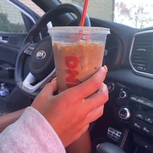  a hand holding a cup of iced coffee
