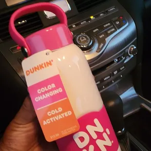  a hand holding a pink and white water bottle