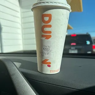  a cup of dunkin donuts on the dashboard of a car