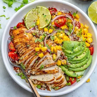  a white bowl filled with chicken, rice, avocado, and corn