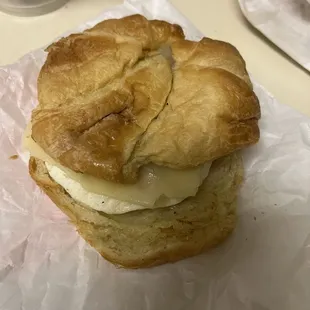  a croissant sandwich on a piece of wax paper
