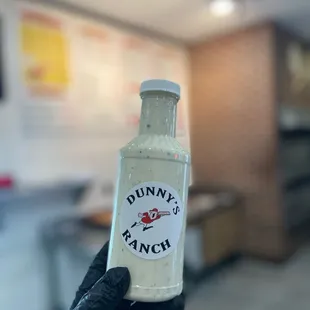 a hand holding a bottle of sauce