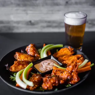 a plate of buffalo wings with dipping sauce and celery