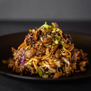 a plate of noodles with meat and vegetables