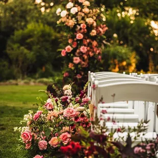 a row of white chairs with pink and red flowers