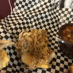 ows a pulled pork sandwich with a side of barbecue sauce