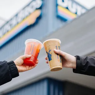 two hands holding two cups of coffee