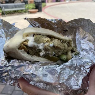 a hand holding a pita sandwich