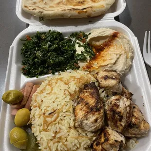 Chicken kebab plate with hummus, tabbouleh and pita bread.