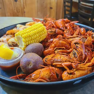 a plate of crawfish, potatoes, corn, and potatoes